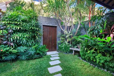a garden with a wooden door in the middle of a yard at Villa Anjali Purple by Villa Finder in Seminyak