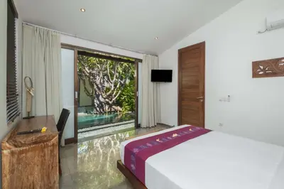 a bedroom with a bed and a large window at Villa Anjali Purple by Villa Finder in Seminyak