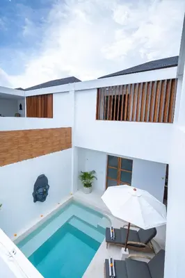 a house with a swimming pool and an umbrella at Villa Mandara Double Six in Legian