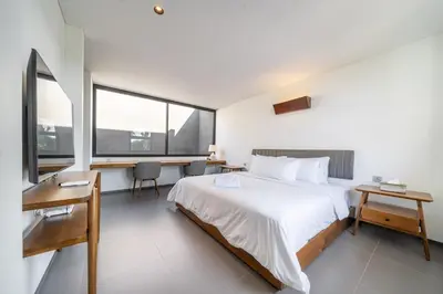 a bedroom with a large white bed and a desk at Casa Nadi in Seminyak