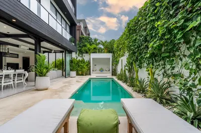 an outdoor swimming pool in a building with plants at Villa Vantage 8, Umalas in Kerobokan