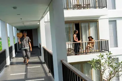 a man walking down a building with a sign in his hand at d'primahotel Petitenget Seminyak 2 in Seminyak