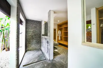 a bathroom with a walk in shower next to a window at Abaca Villas in Seminyak