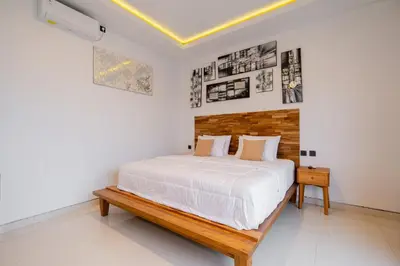 a white bedroom with a bed and a wooden bench at Danbi Villa Bali By Bali Cabin in Canggu