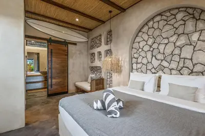 a bedroom with a large bed with a stone wall at Brand New 4BR Villa with Pool, Sauna & Fire pit close to Nusa Dua and Uluwatu in Jimbaran