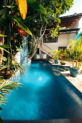 a swimming pool in the middle of a yard with plants at Bali Akasa Villa in Seminyak