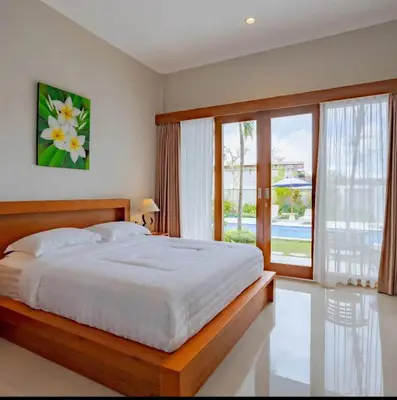 a bedroom with a large bed and a large window at Sari alam guest house in Kerobokan