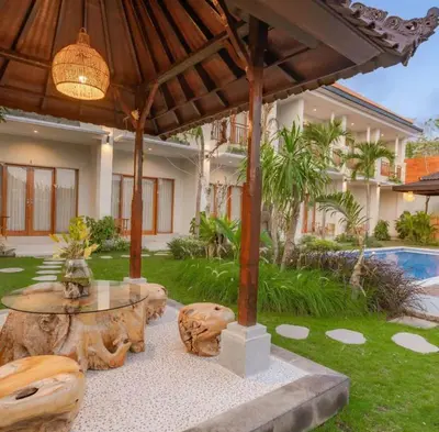 a patio with a table and chairs and a house at Sari alam guest house in Kerobokan
