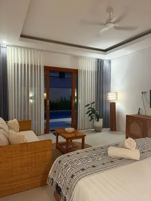 a bedroom with a bed and a couch and a table at Santai Suites Nusa Dua-Child Free in Nusa Dua