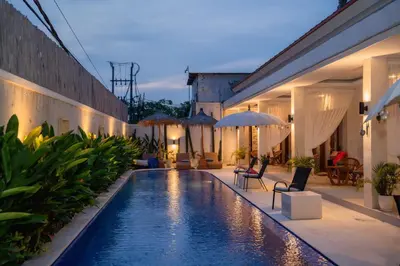 a pool with chairs and umbrellas next to a building at Santai Suites Nusa Dua-Child Free in Nusa Dua