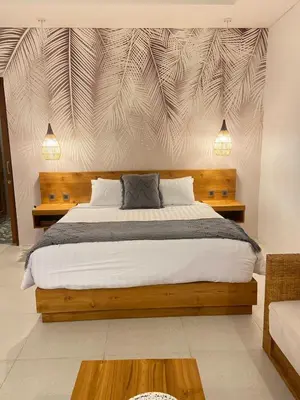 a bedroom with a large bed with a wooden headboard at Santai Suites Nusa Dua-Child Free in Nusa Dua