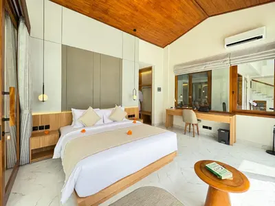 a bedroom with a large bed and a desk at The Aurum Canggu Villas by Nagisa Bali in Canggu