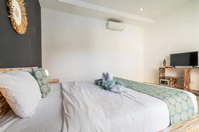 a bedroom with a bed with a pillow and a tv at Villa Azure 3 - Tropical 4-Bedroom Pool Villa Near Seminyak in Seminyak
