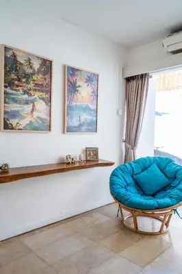 a room with a blue chair and a wall with paintings at Villa Azure 2 - Master Suite in shared Pool Villa in Seminyak