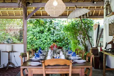 a long wooden table with chairs and an umbrella at Villa Damai Manis in Seminyak
