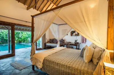 a bedroom with a canopy bed and a pool at Villa Damai Manis in Seminyak