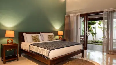 a bedroom with a bed and a green wall at The Clovewood Villa in Seminyak