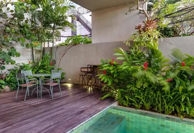 a patio with a table and chairs and plants at Swan Villa R in Seminyak