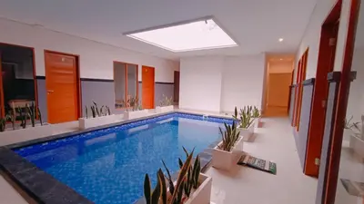 a large swimming pool in a room with plants at Deva Guest House - Kerobokan in Seminyak