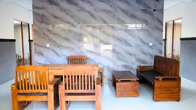 a dining room with wooden tables and chairs and a marble wall at Deva Guest House - Kerobokan in Seminyak