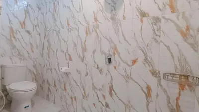 a bathroom with a toilet and a marble wall at Deva Guest House - Kerobokan in Seminyak