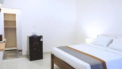 a bedroom with a large bed and a small cabinet at Deva Guest House - Kerobokan in Seminyak