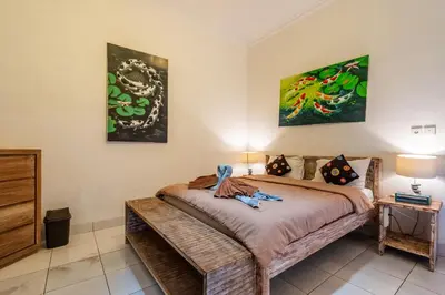 a bedroom with a bed and two paintings on the wall at 3-Bedroom Villa near Kudeta Beach - Oberoi Street By iBali Management in Seminyak