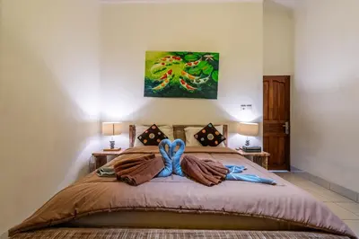 a bedroom with a bed with a painting on the wall at 3-Bedroom Villa near Kudeta Beach - Oberoi Street By iBali Management in Seminyak