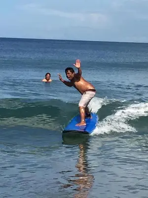 a man riding a wave on a surfboard in the ocean at inadreadboy surfclass in Legian