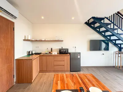 a kitchen with wooden cabinets and a black refrigerator at Olala Loft Seminyak in Seminyak