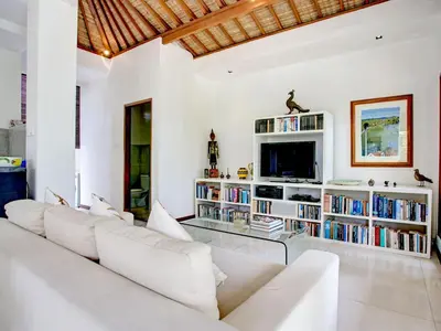 a living room with white furniture and a tv at Villa Shanti, Sitara Villa Group in Seminyak
