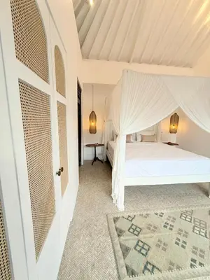 a bedroom with a white bed with a mosquito net at Villa Gamelan Bohème Chic Bali in Seminyak
