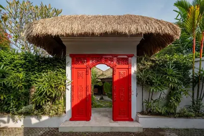 a red door on a building with a straw roof at Tropical Oasis of Calm in the Heart of Seminyak, 4BR Villa Luisha in Seminyak