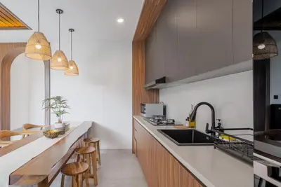 a kitchen with a sink and a counter with stools at Villa Loema in Kerobokan