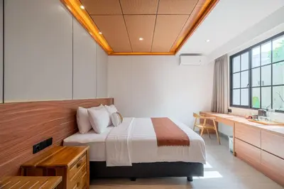 a bedroom with a bed and a desk and a window at Villa Loema in Kerobokan