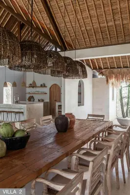 a dining room with a long wooden table and chairs at Villa Massilia Bali in Seminyak