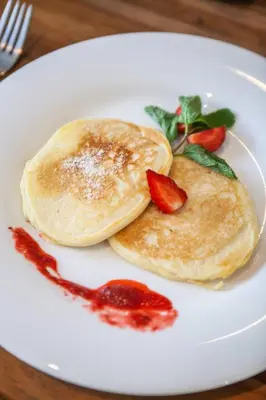 two pancakes on a white plate with strawberry sauce at Modern 4bd villa, amazing location in Seminyak in Seminyak