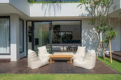 a patio with white chairs and a wooden table at Luxurious 5 bd villa in Seminyak - art deco style in Canggu