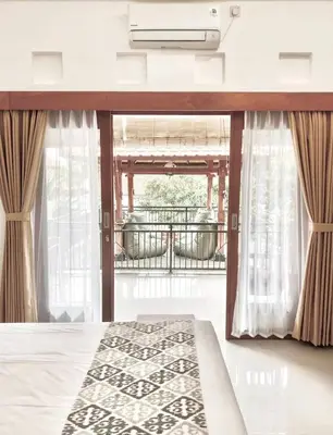 a bedroom with a bed and a balcony at Wresni guesthouse in Canggu
