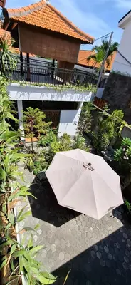 a white umbrella sitting on a walkway next to a building at Wresni guesthouse in Canggu
