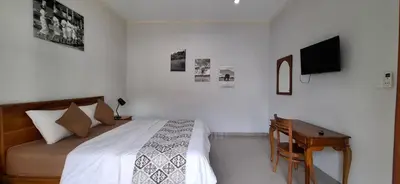 a white bedroom with a bed and a desk at Wresni guesthouse in Canggu