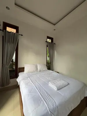 a white bed in a room with two windows at Graha Shanti Guest House in Pulau Serangan