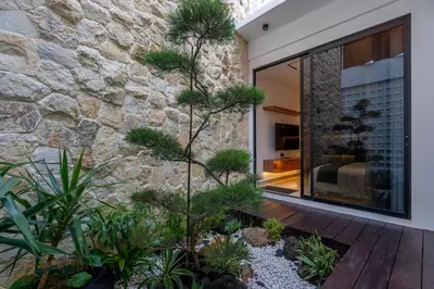 a courtyard with plants and a stone wall at 2BR Modern Suites near Airport in Pesanggaran