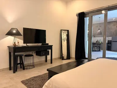 a bedroom with a bed and a desk with a television at Villa Casa Mari in Seminyak