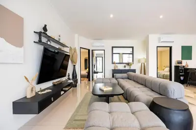 a living room with a large couch and a tv at Damai Suite Relax & Comfort in Canggu 3BR in Canggu