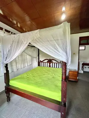 a green bed with a canopy in a room at Nyoman Legian House in Legian