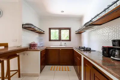 a large kitchen with wooden cabinets and a sink at Villa Vista 2 Seminyak in Seminyak