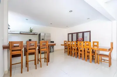 a kitchen with wooden chairs and a table and a refrigerator at Villa Vista 2 Seminyak in Seminyak