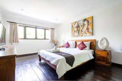 a bedroom with a bed and a desk and window at 9 Bedroom Villa Vista Seminyak in Seminyak