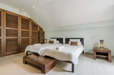 two beds in a large room with wooden cabinets at 9 Bedroom Villa Vista Seminyak in Seminyak